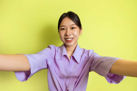 Happy Asian Lady Making Selfie Posing Standing Over Yellow Backgroundの写真素材