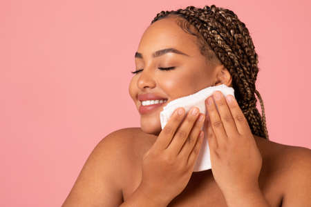 African American Lady Drying Face With Towel Over Pink Backgroundの写真素材
