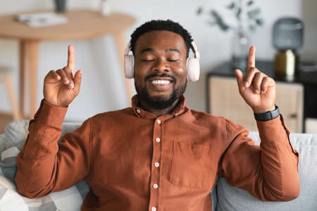 Black Man Listening To Music Wearing Earphones Relaxing At Home