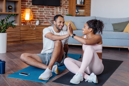 Glad millennial african american male and female in sportswear giving high five for excellent workout resultの写真素材