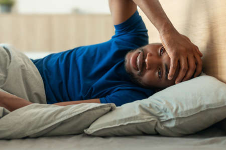 Black Man Touching Head Having Insomnia And Headache In Bedroomの写真素材