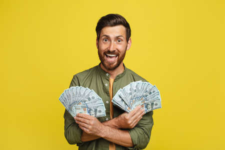 Big luck and win concept. Portrait of happy man holding a lot of dollar cash, celebrating success and posing with moneyの写真素材