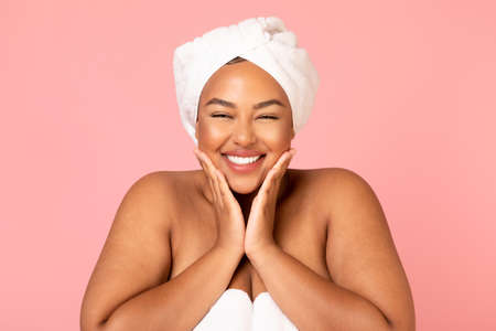 Happy Overweight African American Woman Touching Face On Pink Backgroundの写真素材