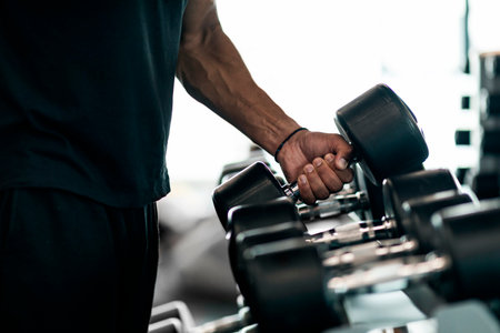 Sport Equipment. Unrecognizable Black Male Athlete Taking Dumbbell From Rack At Gymの写真素材