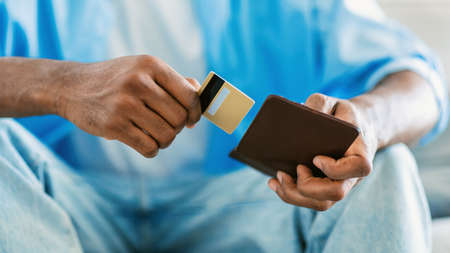 Finance and electronic money. Unrecognizable african ameican man taking credit card out of wallet,...