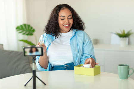 Cheerful African American Blogger Lady Making Video On Cellphone Indoorsの写真素材