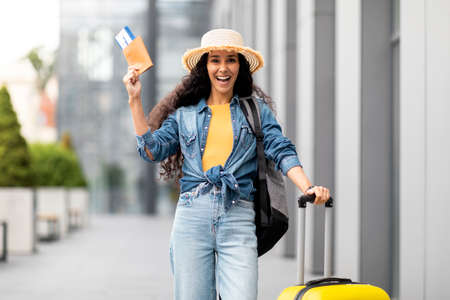 Excited young woman going vacation alone, showing passport