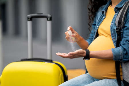 Cropped of pregnant woman traveller using disinfectant sprayの写真素材