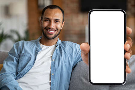 Place For Ad. Cheerful Black Man Demonstrating Blank Smartphone With White Screen