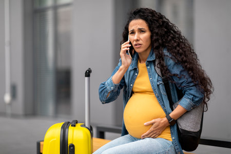 Worried expecting woman travelling alone, having phone callの写真素材