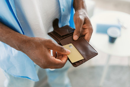 Unrecognizable black guy taking out credit card from his wallet, standing at home, closeup, copy spaceの写真素材