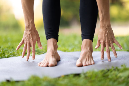 Legs and hands of unrecognizable sporty woman touching mat