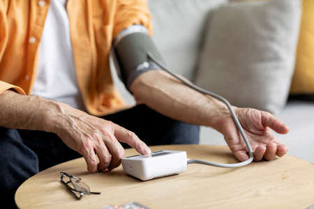 Unrecognizable senior man checking blood pressure at home