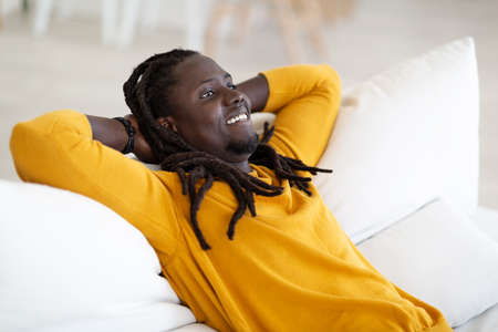Home Relax. Smiling Black Guy Resting On Couch In Living Room
