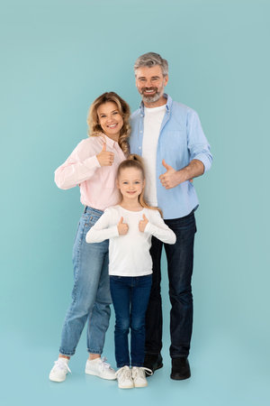 Vertical Shot Of Family Gesturing Thumbs Up On Blue Background