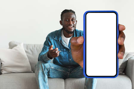 Black Man Showing Huge Cellphone With Blank Screen Sitting Indoor