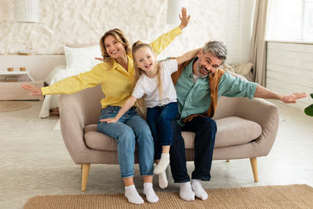 Family With Preschool Daughter Having Fun Posing Spreading Hands Indoorの写真素材