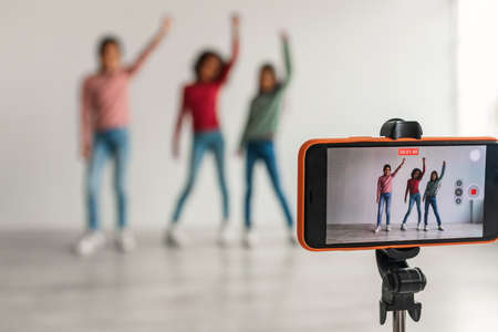 Three Kid Girls Bloggers Posing Making Video Via Phone Indoorsの写真素材