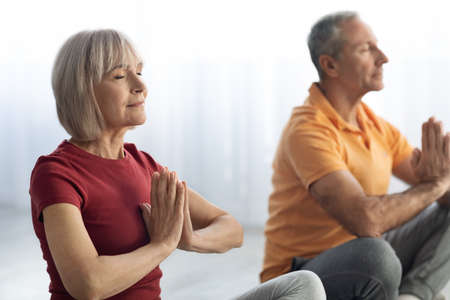 Closeup of senior man and woman practicing meditation togetherの写真素材