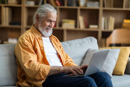 Side view of elderly man using computer at home