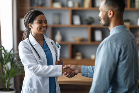 Cheerful african american woman doctor greeting patientの写真素材