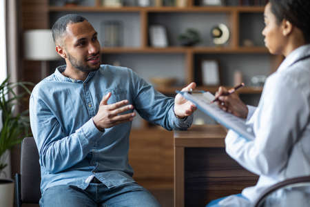 Young african american guy having appointment with general practitionerの写真素材