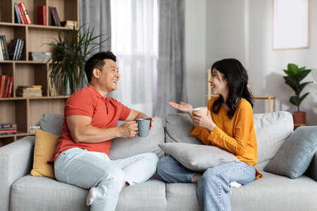 Relaxed chinese lovers enjoying conversation, drinking coffeeの写真素材