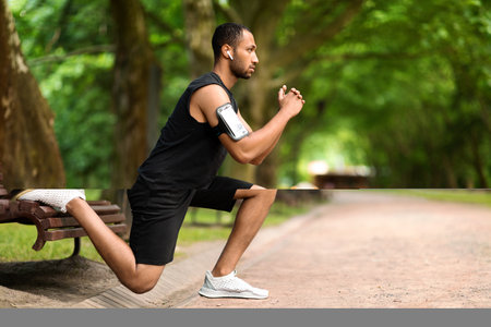 Motivated muscular black man exercising in the park, side view