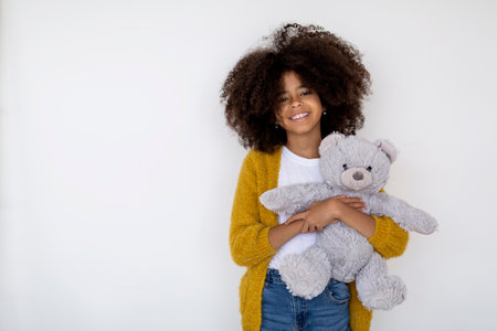 Cheerful african american girl posing with her toy on whiteの写真素材