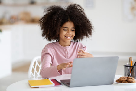 Cute african american school girl using laptop at homeの写真素材
