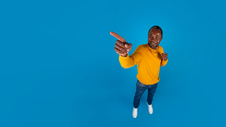 Happy black man pointing at copy space, full length