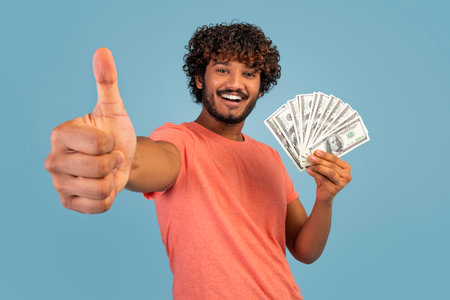 Cheerful indian man showing cash and thumb upの写真素材