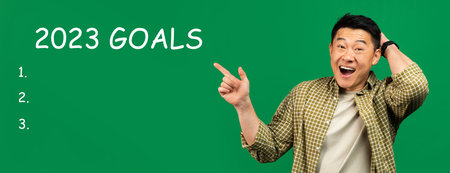 Cheerful shocked adult asian man point finger at 2023 goals with light bulbs, checklist with free spaceの写真素材