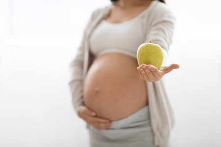 Cropped of pregnant lady holding green apple on whiteの写真素材