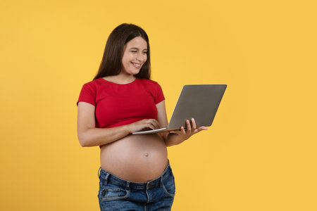 Pregnancy And Technology. Happy Young Pregnant Woman Using Laptop Computerの写真素材