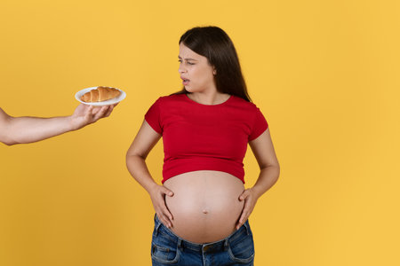 Hand Offering Plate With Croissant To Confused Pregnant Womanの写真素材