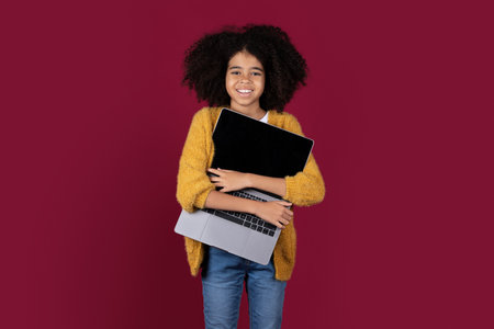Happy black kid embracing modern laptop on colorful backgroundの写真素材