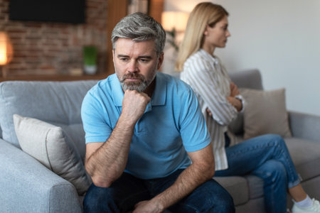 Unhappy middle aged european man ignores offended lady after quarrel in living room interiorの写真素材