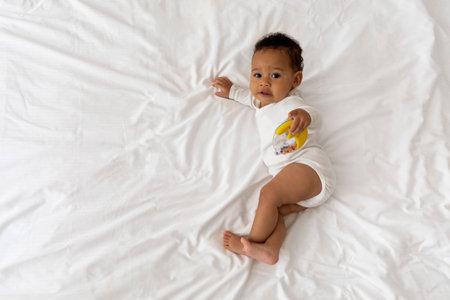 Cute Black Baby Playing With Toys While Relaxing On Bed At Home