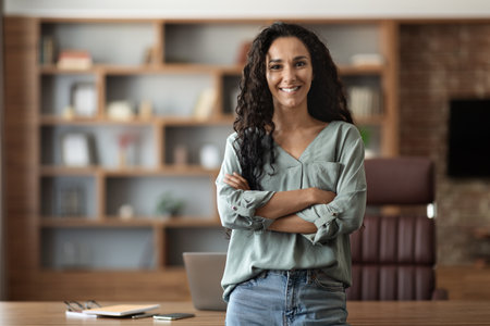 Happy young woman posing at office, smiling at cameraの写真素材