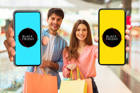Couple Showing Cellphones With Black Friday Sale Offer In Mall