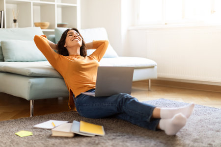 Happy Young Arab Woman Relaxing On Floor After Study Online With Laptopの写真素材