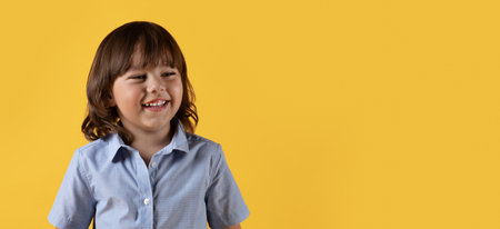 Cute happy little boy looking aside and laughing, enjoying great news, orange background with empty space, panoramaの写真素材