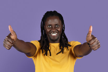 Happy black man showing thumb ups and smiling on purple
