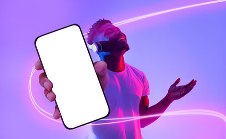 Emotional african american man listening to music, showing smartphone, mockupの写真素材