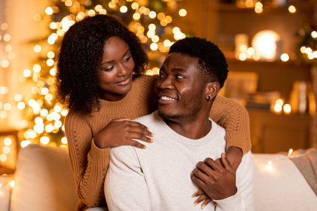 Cheerful millennial african american woman hugging man, enjoy holiday together in living room interiorの写真素材