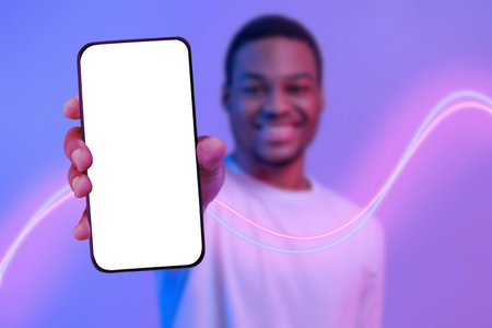 Smiling african american guy showing smartphone with blank screenの写真素材