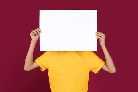 Unrecognizable african american child hiding behind empty placardの写真素材