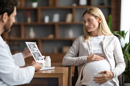 Male Gynecologist Doctor Showing Baby Sonography Image To Worried Pregnant Womanの写真素材