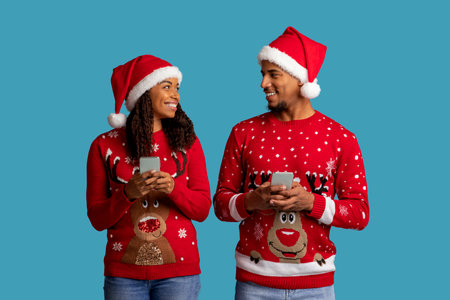 Loving Christmas black couple using cell phone isolated on blue